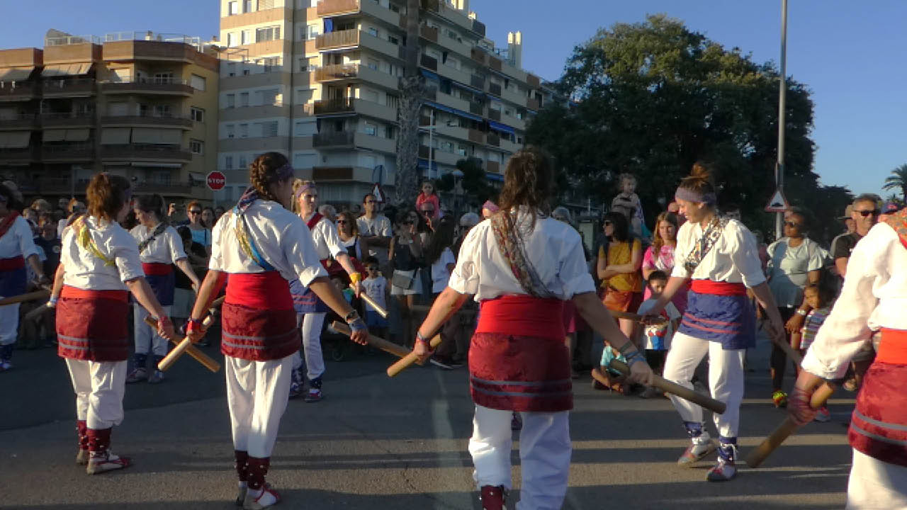 colourful photo of a group of dancers, holding sticks